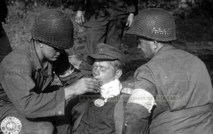 9th Division men aid German wounded soldier